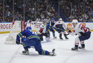 Vancouver Canucks' Elias Lindholm, front left, misses the pass as Washington Capitals goalie Charlie Lindgren, back left, Hendrix Lapierre, front right, and Vancouver's Nils Hoglander, back center, watch during the third period of an NHL hockey game in Vancouver, British Columbia, Saturday, March 16, 2024. (Darryl Dyck/The Canadian Press via AP)