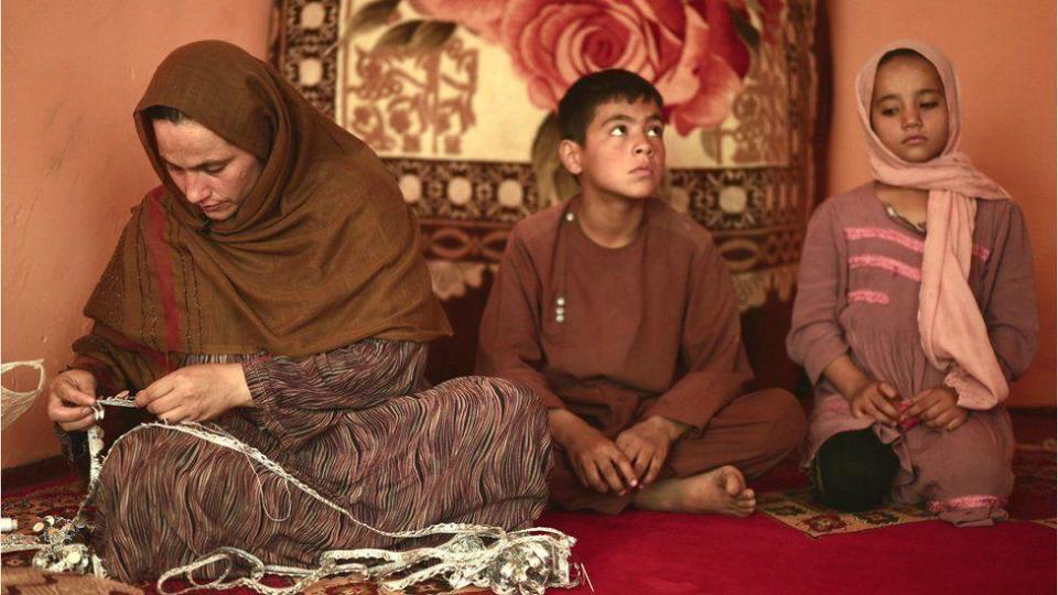 Una madre tejiendo junto a sus hijos.