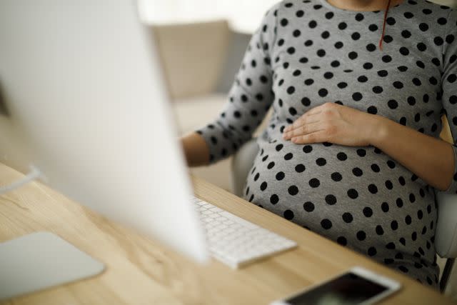 damircudic / Getty Images Pregnant woman working in an office