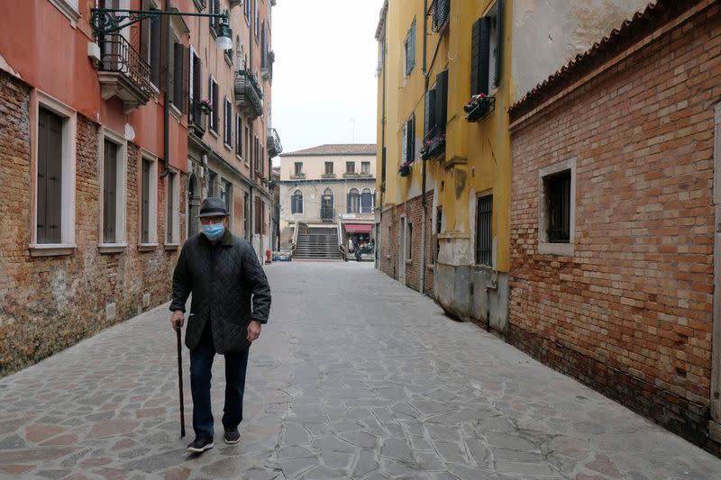 An elderly man with a protective mask walks in Venice