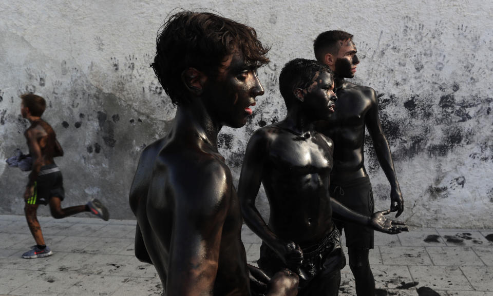 In this photo taken on Friday, Sept. 6, 2019, boys painted with black grease celebrate during the traditional festivities of the Cascamorras festival in Baza, Spain. During the Cascamorras Festival, and according to an ancient tradition, participants throw black paint over each other for several hours every September 6 in the small town of Baza, in the southern province of Granada. The "Cascamorras" represents a thief who attempted to steal a religious image from a local church. People try to stop him, chasing him and throwing black paint as they run through the streets. (AP Photo/Manu Fernandez)