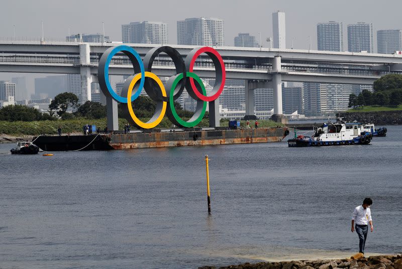 Boats tow the giant Olympic rings, which are being temporarily removed for maintenance, at the waterfront area at Odaiba Marine Park in Tokyo