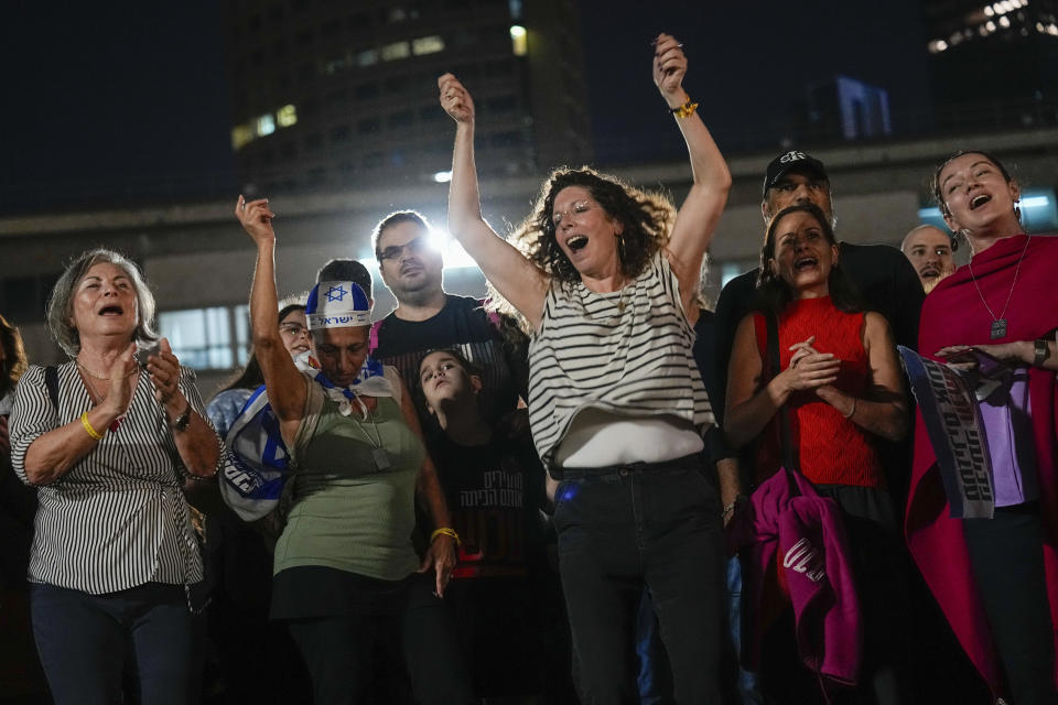 People react as they hear the news of the release of 13 Israeli hostages held by Hamas in the Gaza strip, in Tel Aviv, Israel, on Friday, Nov. 24, 2023. Friday marks the start of a four-day cease-fire in the Israel-Hamas war, during which the Gaza militants pledged to release 50 hostages in exchange for 150 Palestinians imprisoned by Israel. (AP Photo/Ariel Schalit)