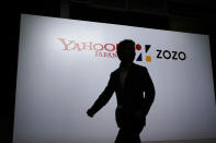 A man is silhouetted as he walks past logos of Yahoo Japan and Zozo during a news conference on Thursday, Sept. 12, 2019, in Tokyo. (AP Photo/Jae C. Hong)