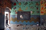 A man stands on the door of a partially damaged classroom after the school building was attacked by a mob in a riot affected area following clashes between people demonstrating for and against a new citizenship law in New Delhi