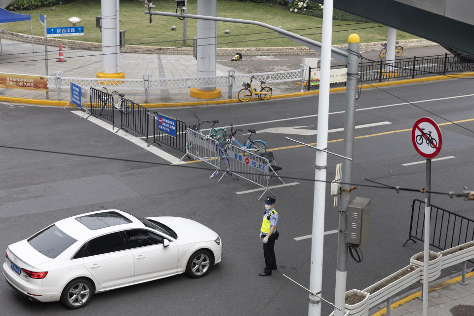 A police officer checks on a vehicle passing through a police checkpoint in Shanghai on Friday, May 27, 2022. Residents in China's largest city of Shanghai have become bolder in demanding the lifting or easing of coronavirus restrictions that have left millions locked up in their compounds for almost two months. (AP Photo/Andrew Braun)