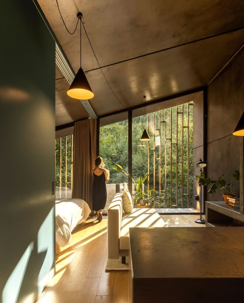 Woman peers out a large glass wall in her Paradihna Village Resort cabin to take in the views. 