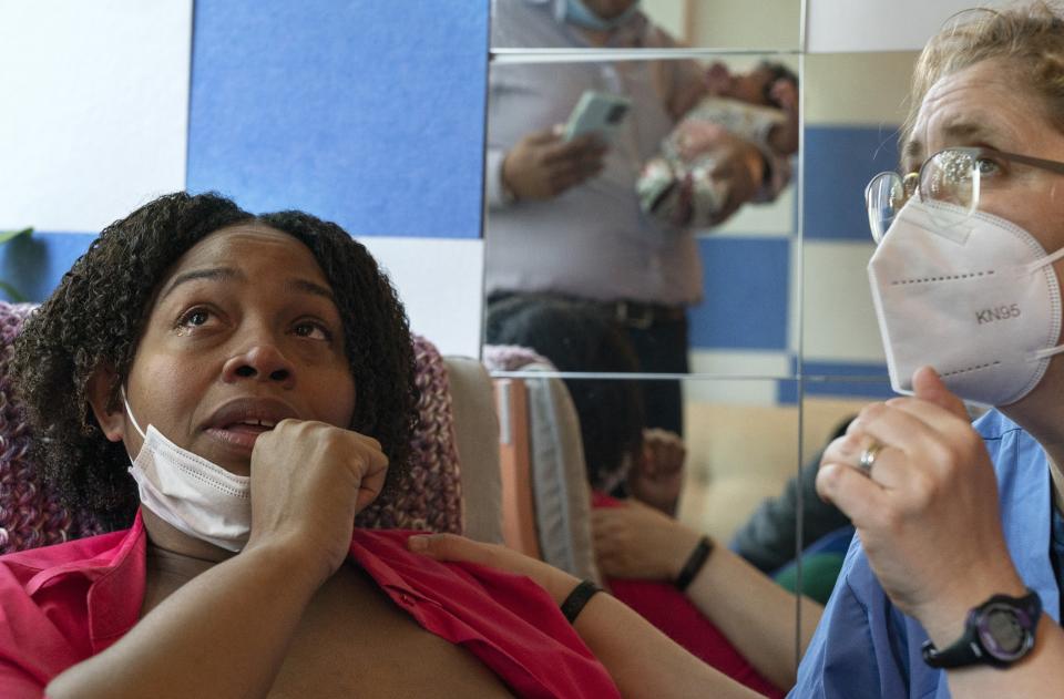 Capri Isidoro, of Ellicott City, Md., left, looks up at her husband and baby as she is overwhelmed with emotion as Ann Faust, an International Board Certified Lactation Consultant (IBCLC), tells her that she feels Isidoro can exclusively breastfeed if she so desires, Monday, May 23, 2022, as part of a lactation consultation in Columbia, Md., at Baby and Me Lactation Services. Baby Charlotte was delivered via emergency c-section and given formula at the hospital. Isidoro has been having trouble with breastfeeding and has been searching for a formula that her daughter can tolerate well. "If all things were equal I would feed her with formula and breastmilk," says Isidoro, "but the formula shortage is so scary. I worry I won't be able to feed my child." (AP Photo/Jacquelyn Martin)