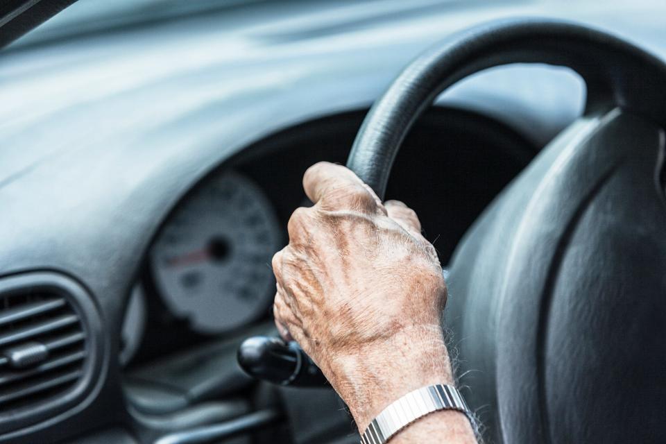 Anonymous hand of a 93 year old elderly senior adult man gripping and turning his steering wheel. He is still independent, and he finds an excuse to drive his car almost every day.