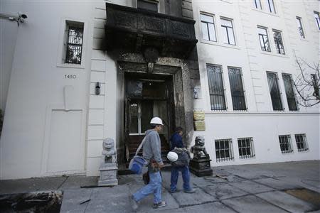 Construction workers walk past the damaged front of the Chinese consulate after an unidentified person set fire to the main gate in San Francisco, California January 2, 2014 REUTERS/Stephen Lam