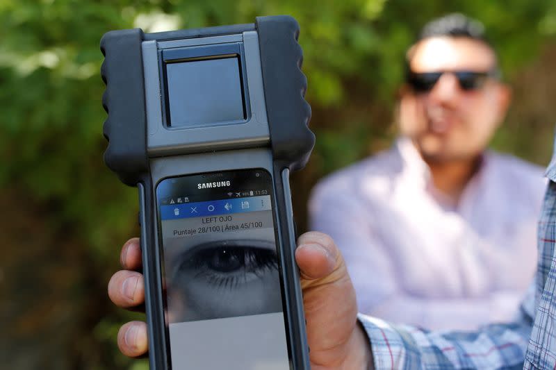 An agent of the U.S. Department of Homeland Security shows a retinal scanner, tested on a fellow agent, at a checkpoint of the Guatemala's border police (DIPAFRONT) in El Progreso