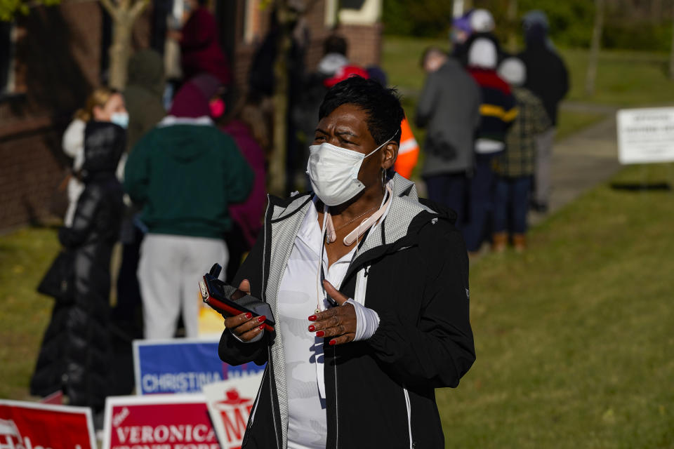 An election worker announces a list of nearby poling places with shorter wait times as voters wait in a line to vote at a polling place in Indianapolis, Tuesday, Nov. 3, 2020. (AP Photo/Michael Conroy)