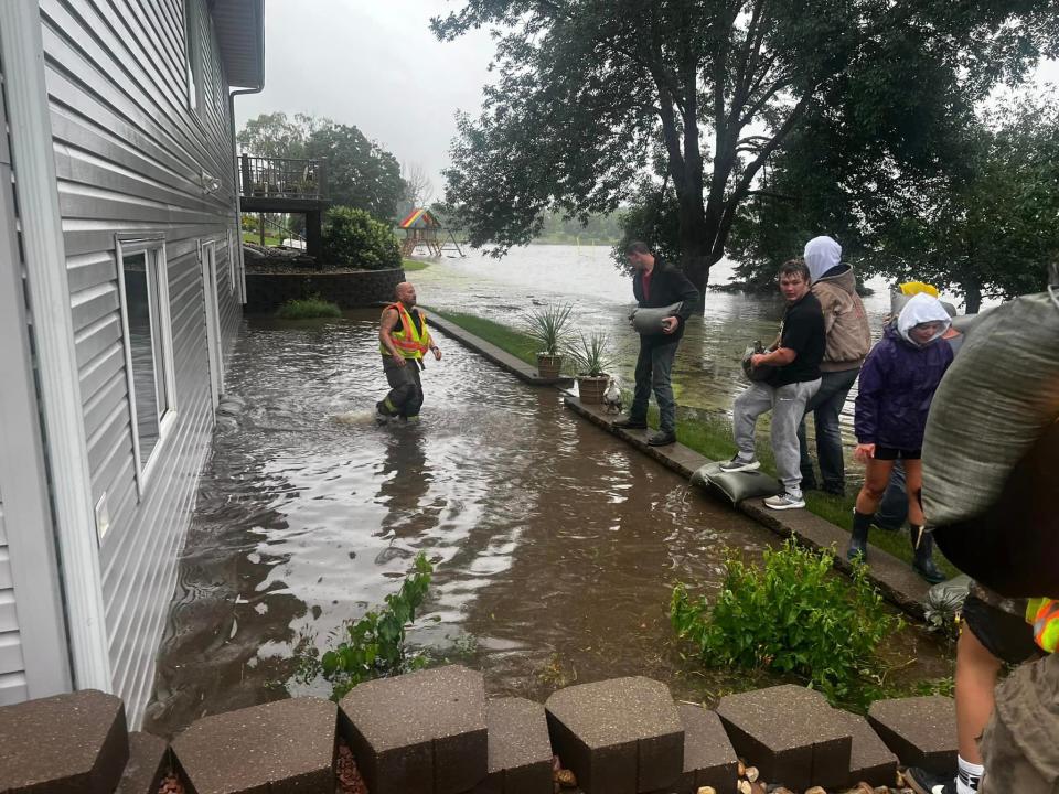 Canton residents help pile sand bags near a home as water from Christmas Lake in Canton rises Thursday, June 20, 2024.