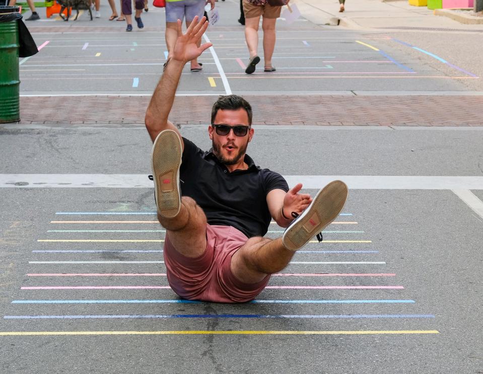 With Albert Avenue opened up with games like hop-scotch and  this long jump,  a man takes a spill as his shoes fail him at the East Lansing Art Festival Sunday, Aug. 8, 2021.