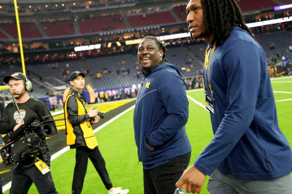 Former Michigan quarterback Denard Robinson, center, smiles at someone in the stands as he walks in with the Michigan football team before the start of the College Football Playoff national championship game at NRG Stadium in Houston on Monday, Jan. 8, 2024.