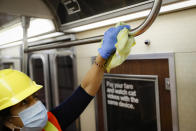 A contractor cleans a subway car at the 96th Street station to control the spread of COVID-19, Thursday, July 2, 2020, in New York. Mass transit systems around the world have taken unprecedented — and expensive — steps to curb the spread of the coronavirus, including shutting down New York subways overnight and testing powerful ultraviolet lamps to disinfect seats, poles and floors. (AP Photo/John Minchillo)