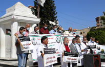 Medical workers wear face masks and hold placards while staging a sit-in protest at the Unknown Soldier Square in Gaza City, Wednesday, Oct. 21, 2020. Arabic reads: "Makassed Hospital is a national address for the Palestinian people." "We call on President Abu Mazen to intervene and bring us back to work." Seven medical workers from the Gaza Strip said Wednesday an Israeli travel ban deprived them from getting to the east Jerusalem hospital where they worked for many years and the hospital eventually fired them. (AP Photo/Adel Hana)