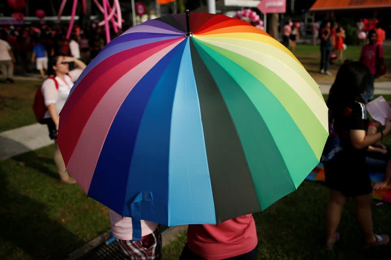 FILE PHOTO: Participants shield themselves from the sun under a rainbow-coloured umbrella before taking part in the forming of a giant pink dot at the Speakers' Corner in Hong Lim Park in Singapore