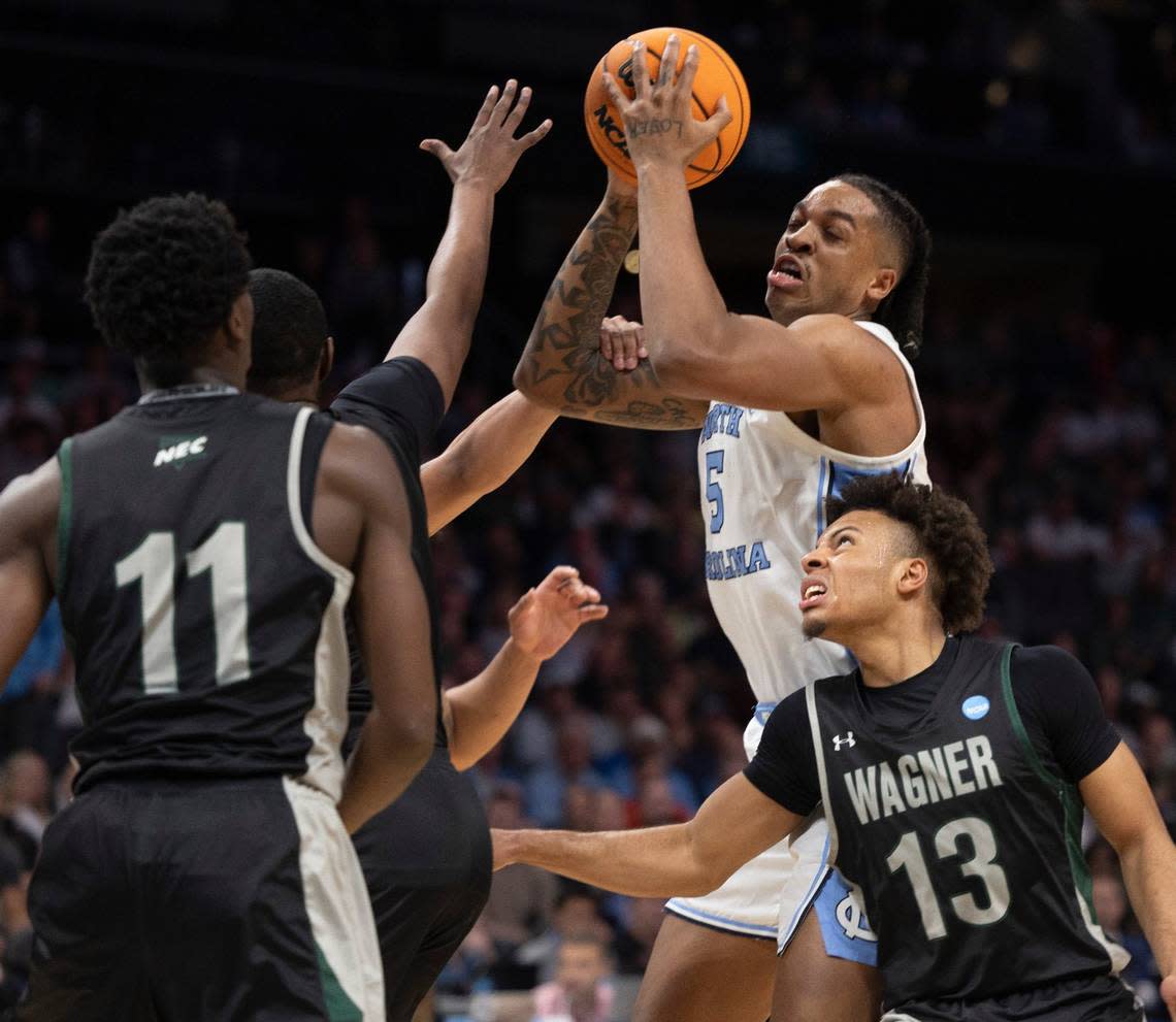 North Carolina’s Armando Bacot (5) secures one of his game high 15 rebounds over Wagner’s Tyje Kelton (4), Melvin Council Jr. (11) and Julian Brown (13) in the first half on Thursday, March 21, 2024 during the NCAA Tournament at Spectrum Center in Charlotte, N.C.