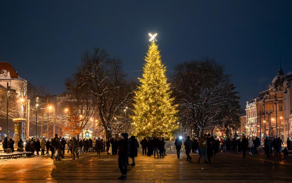 People walk on the Svobody (Freedom) Avenue near the Christmas tree and the opera house in Lviv, Ukraine