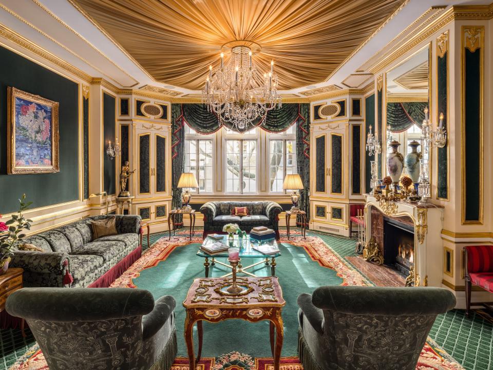 A formal entertaining room that has emerald carpets, gold trim, and a crystal chandelier