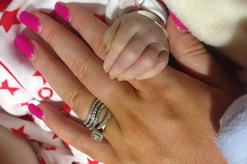 Mum Jess Evans holding Teddy's hand