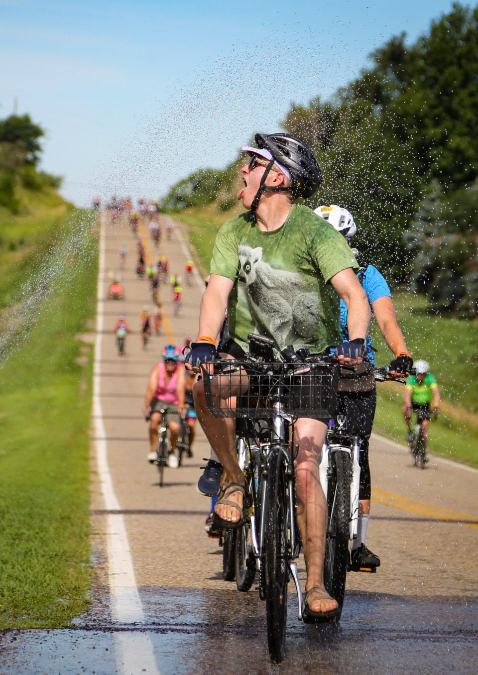 Riders roll though a sprinkler on the way to meeting town Anthon on Sunday, the first day of RAGBRAI 2022.