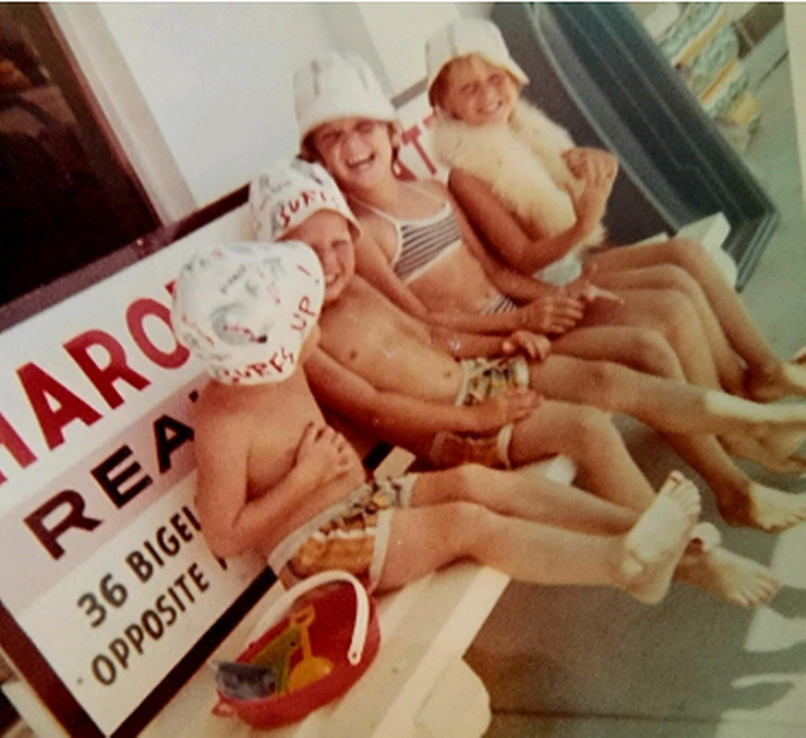 Kimberly sits with her sisters, Kathy and Kelly, and their brother Sean in front of another surf shop on Fort Myers beach that did survive Hurricane Ian.