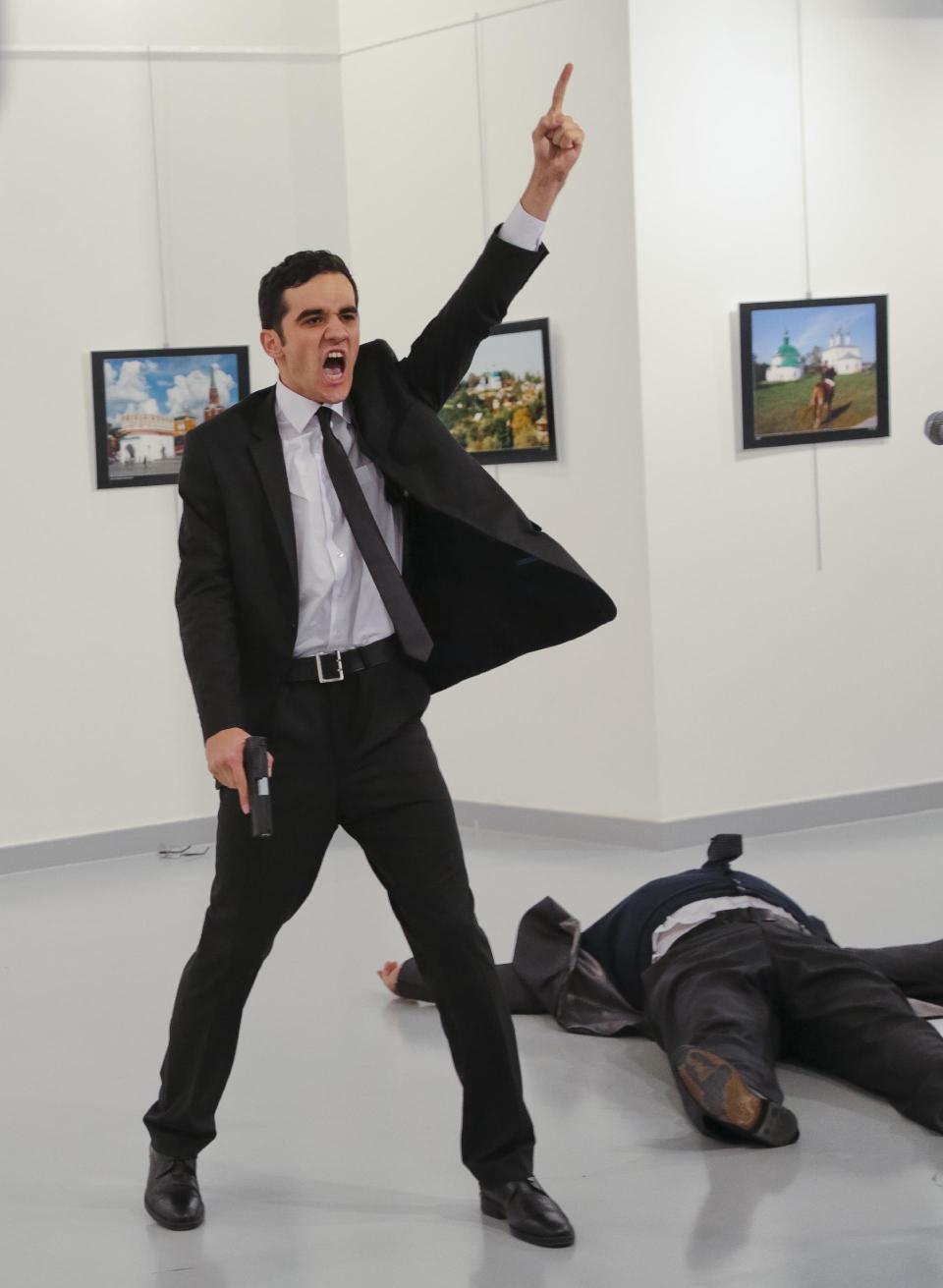 An unnamed gunman gestures after shooting the Russian Ambassador to Turkey, Andrei Karlov, at a photo gallery in Ankara, Turkey, Monday, Dec. 19, 2016. A gunman opened fire on Russia's ambassador to Turkey at a photo exhibition on Monday. The Russian foreign ministry spokeswoman said he was hospitalized with a gunshot wound. (AP Photo/Burhan Ozbilici)