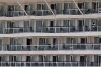 People stand on the balconies of their cabins, of a cruise ship that has been docked for almost two months due to the coronavirus outbreak at the port of Piraeus, near Athens, Wednesday, May 20, 2020. Greece's government says revenue from its vital tourism industry has been hammered as a result of the COVID-19 pandemic and lockdown measures, adding that detailed guidelines on how the season will operate will be announced Wednesday. (AP Photo/Thanassis Stavrakis)