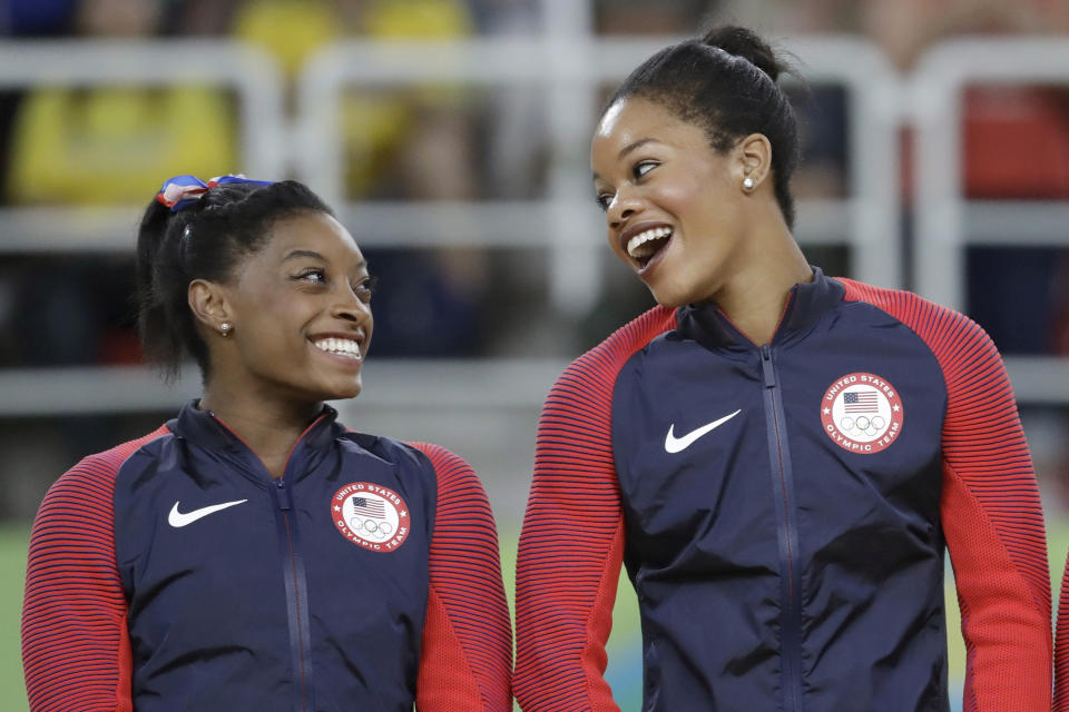 FILE - U.S. gymnasts and gold medallists, Simone Biles, left and Gabby Douglas celebrate on the podium during the medal ceremony for the artistic gymnastics women's team at the 2016 Summer Olympics in Rio de Janeiro, Brazil. Douglas is the second Olympic champion in recent weeks to say they are pointing toward Paris. Simone Biles, who won the all-around gold in Rio and was teammates with Douglas on the five-woman U.S. squad that cruised to the team gold in Brazil, is returning to competition at the U.S. Classic in Chicago in early August. (AP Photo/Julio Cortez, File)