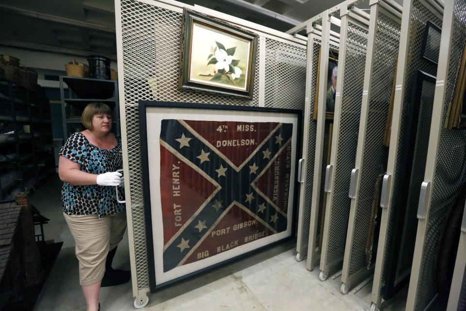 In this Oct. 11, 2013 photograph, Cindy Gardner, Director of Collections and Museum Division Project Manager, for the Museum of Mississippi History at the Mississippi Department of Archives and History shows off a Confederate battle flag and era painting that will be among the items that will eventually be displayed in the state history museum that will be built along side a museum documenting civil rights in the state, in Jackson, Miss. The two museums will have more than 200,000 square feet combined and are to be built not far from the Capitol in Jackson. The state has committed $40 million to the museums, and Hank Holmes said officials are trying to raise $14 million in private donations. (AP Photo/Rogelio V. Solis)