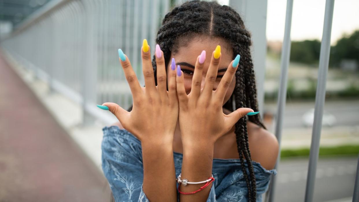 model on city bridge posing with colorful nails