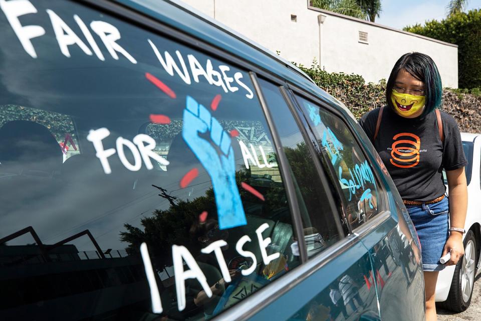 Crystal Kan, a storyboard artist, draws pro-labor signs on cars of union members during a rally at the Motion Picture Editors Guild IATSE Local 700 on Sunday, Sept. 26, 2021 in Los Angeles, CA. Up to 60,000 members of the International Alliance of Theatrical Stage Employees (IATSE) might go on strike in the coming weeks over issues of long working hours, unsafe conditions, less pay from streaming companies and demand for better benefits.