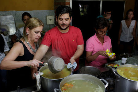 Diego Prada (C), Maria Luisa Pombo (L) and other volunteers of the Make The Difference (Haz La Diferencia) charity initiative prepare soup to be donated, at Maria Luisa's kitchen in Caracas, Venezuela March12, 2017. REUTERS/Marco Bello