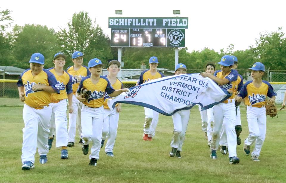 Members of the Williston 11-12 All-Stars run around the field with the District 1 championship banner after their come from behind 13-9 win over Addison County on Tuesday night at Burlington's Schifilliti Field.