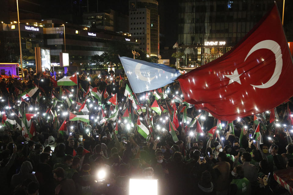 In this photo provided by Turkey's IHH, hundreds of protesters hold up their phones during a rally near Israel's consulate in Istanbul in support of Palestinians, late Tuesday, May 11, 2021. Scores of cars and thousands of people in Istanbul defied a nationwide curfew to demonstrate against Israel's attacks on the Gaza Strip. Rockets streamed out of the Gaza Strip and Israel pounded the territory with airstrikes early Wednesday as the most severe outbreak of violence since the 2014 war took on many hallmarks of that devastating 50-day conflict, with no endgame in sight. (IHH via AP)