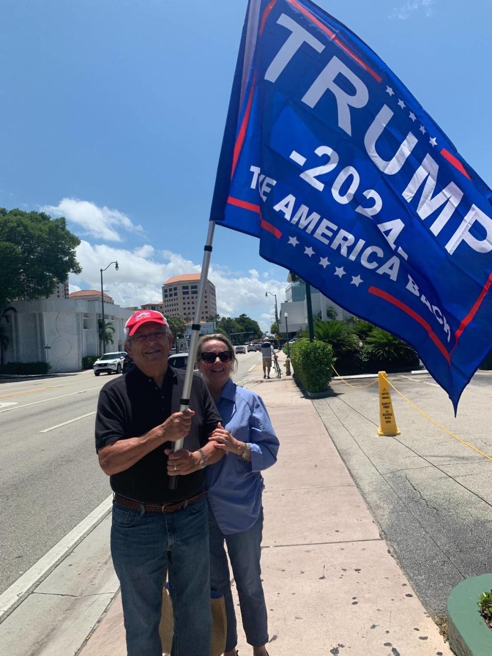 Dr. Enrique Canton and his wife, Rosa Canton, hoist a Trump 2024 flag in front of Versailles restaurant on Southwest Eighth Street in Miami Tuesday, June 13, 2023. They were among a group of Trump supporters who gathered at the famed Little Havana restaurant to possibly catch a glimpse of Trump after his Miami court arraignment on Tuesday afternoon.