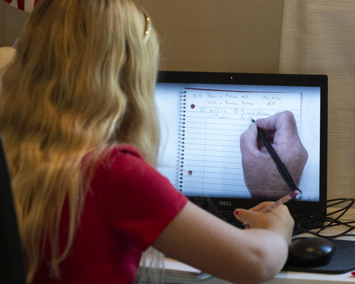 A student looks at her computer screen as her teacher shows a math problem.