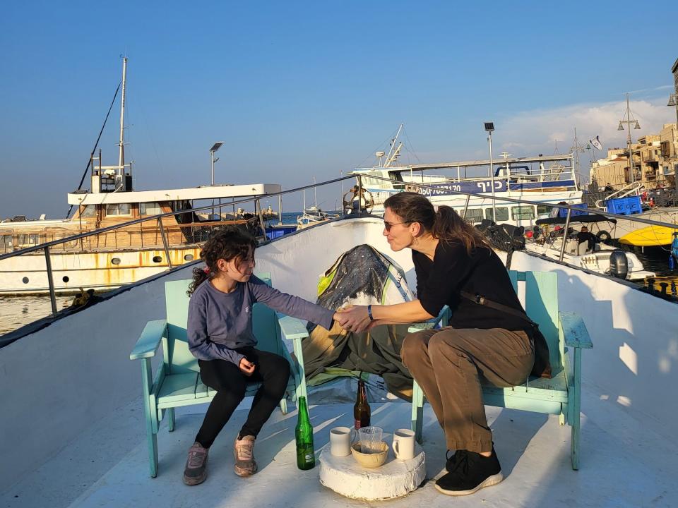 Daughter and mom holding hands and sitting on a boat.