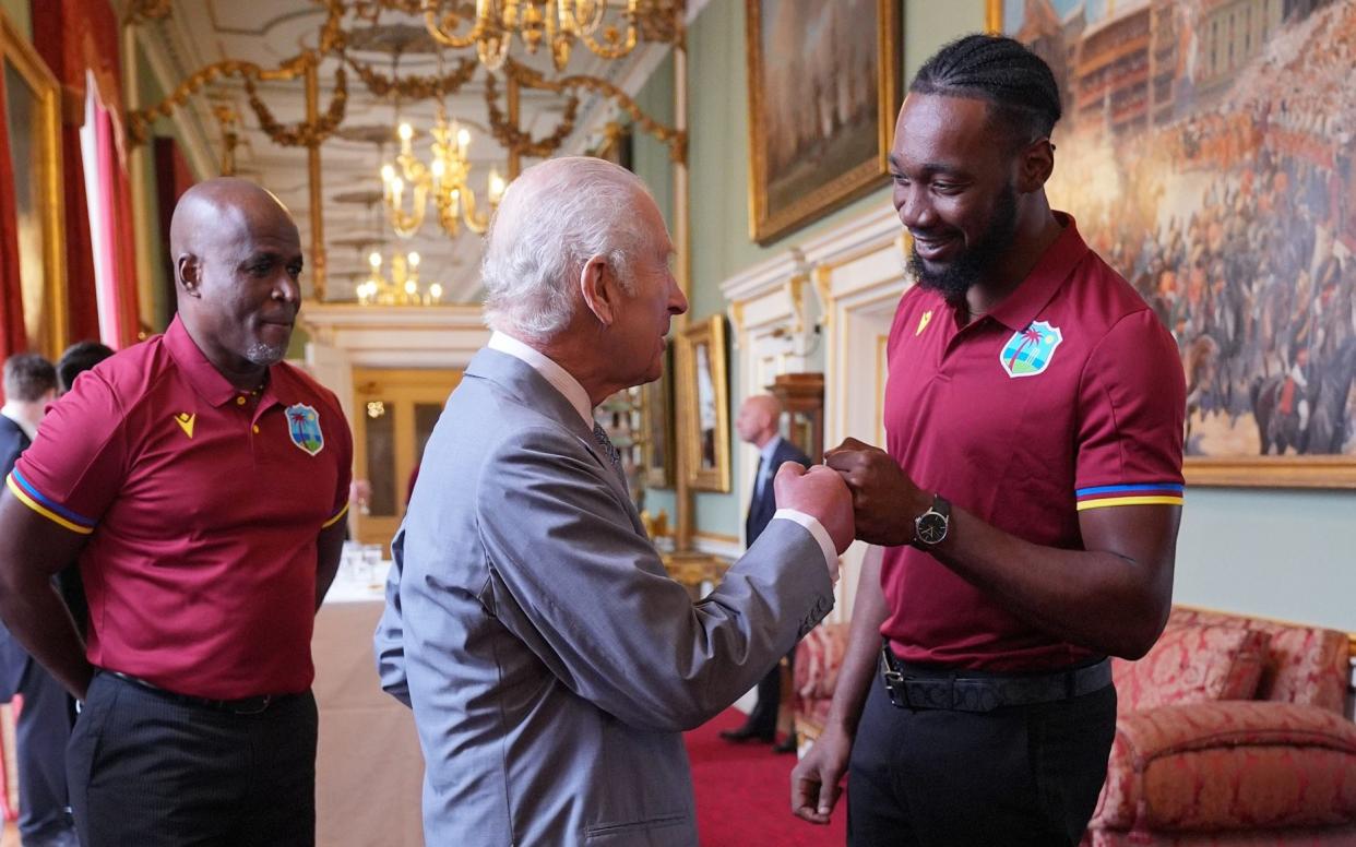 King Charles III shares a fist bump with Mikyle Louis at Buckingham Palace