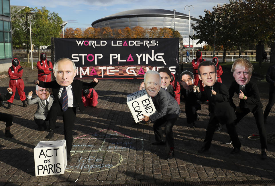 Climate campaigners wearing masks of world leaders enact a "Squid Game" themed protest stunt with a campaigner wearing a mask of Russian President Vladimir Putin, front left, and another wearing a mask of U.S. President Joe Biden, center, on the fringes of the COP26 U.N. Climate Summit, in Glasgow, Scotland, Tuesday, Nov. 2, 2021. The U.N. climate summit in Glasgow gathers leaders from around the world, in Scotland's biggest city, to lay out their vision for addressing the common challenge of global warming. (AP Photo/Scott Heppell)