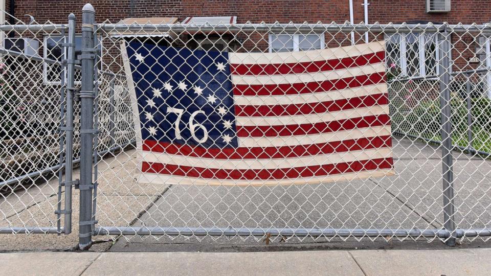 PHOTO: A US bicentenial flag hangs from fence outside a home during Memorial Day in the Queens borough of New York City, May 25, 2020. (Anthony Behar/Sipa USA via AP, FILE)