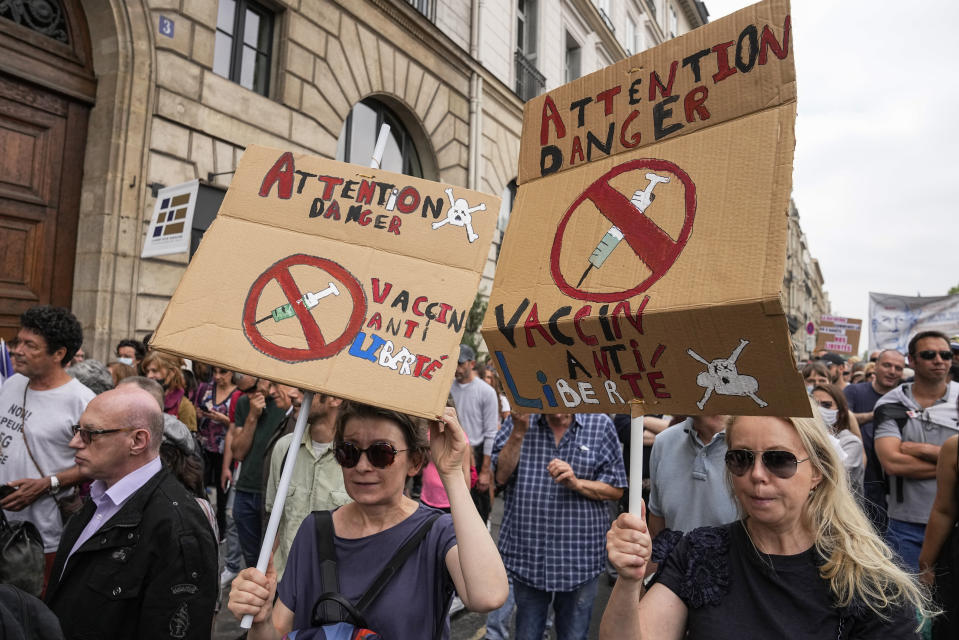 Anti-vaccine protesters hold placards that read attention danger vaccine anti-liberty during a rally in Paris, Saturday, July 17, 2021. Tens of thousands of people protested across France on Saturday against the government's latest measures to curb rising COVID-19 infections and drive up vaccinations in the country. (AP Photo/Michel Euler)