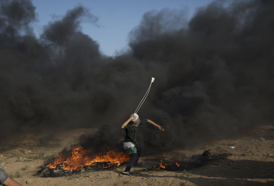 A Palestinian protester hurls stones at Israeli troops during a protest at the Gaza Strip's border with Israel, Friday, Sept.28, 2018. (AP Photo/Khalil Hamra)