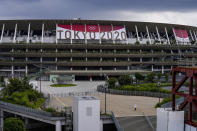 A worker walks through the front entrance of National Stadium Wednesday, June 23, 2021, in Tokyo, one month before the July 23 opening of Tokyo Olympics. The Tokyo Olympics, already delayed by the pandemic, are not looking like much fun: Not for athletes. Not for fans. And not for the Japanese public. They are caught between concerns about the coronavirus at a time when few are vaccinated on one side and politicians who hope to save face by holding the games and the International Olympic Committee with billions of dollars on the line on the other. (AP Photo/Kiichiro Sato)