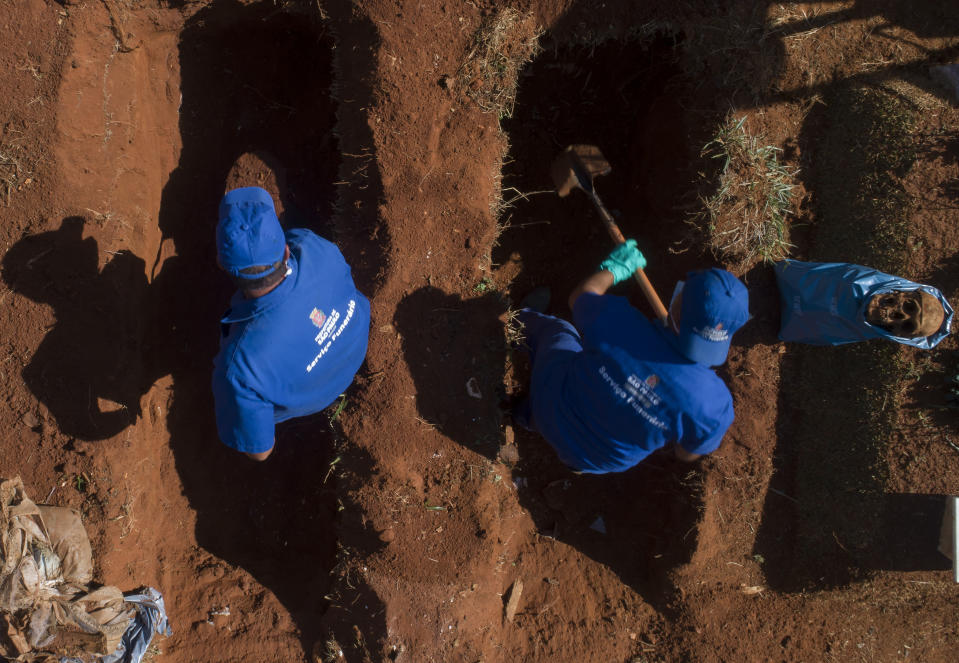 Operarios desentierran restos de personas sepultadas hace tres años en el cementerio de Vila Formosa, que no cobra a las familias por las tumbas, en Sao Paulo, Brasil, el 12 de junio de 2020. Los cuerpos sepultados hace al menos tres años, se exhuman y almacenan en bolsas de plástico para dejar sitio a más féretros, una necesidad más acuciante en la pandemia del coronavirus. (AP Foto/Andre Penner)