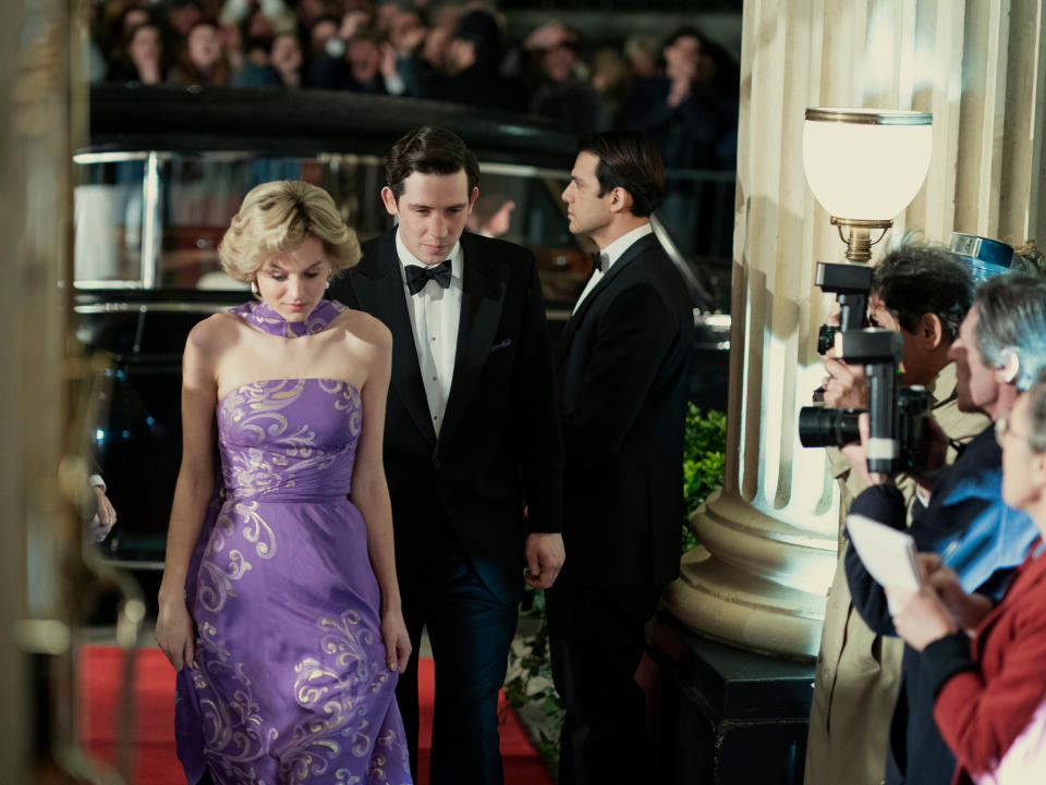 Pincess Diana (Emma Corrin) and Prince Charles (Josh O'Connor) are seen walking by a line of photographersOllie UptonNetflix