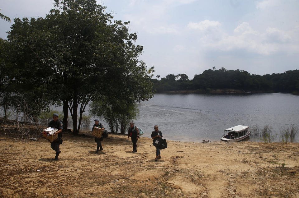 Electoral workers and military police officers unload electronic voting machines to be taken to a polling station a day ahead of the country's general elections, at the Bela Vista do Jaraqui community in Manaus, Amazonas state, Brazil, Saturday, Oct. 1, 2022. (AP Photo/Edmar Barros)