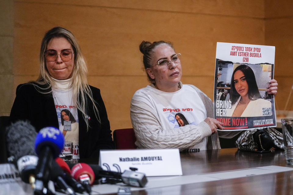Israeli Alin Atias, right, holds a picture of her daughter Amit Buskila who was abducted by Hamas at the Supernova festival and Nathalie Amouyal, left, a family member, calling for the release of hostages who were kidnapped on Oct. 7, 2023 during a media conference in Paris, Tuesday, Feb. 2024. (AP Photo/Michel Euler)